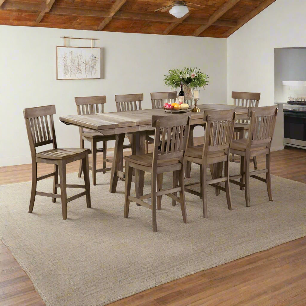Wooden dining table with chairs in a room with large windows.