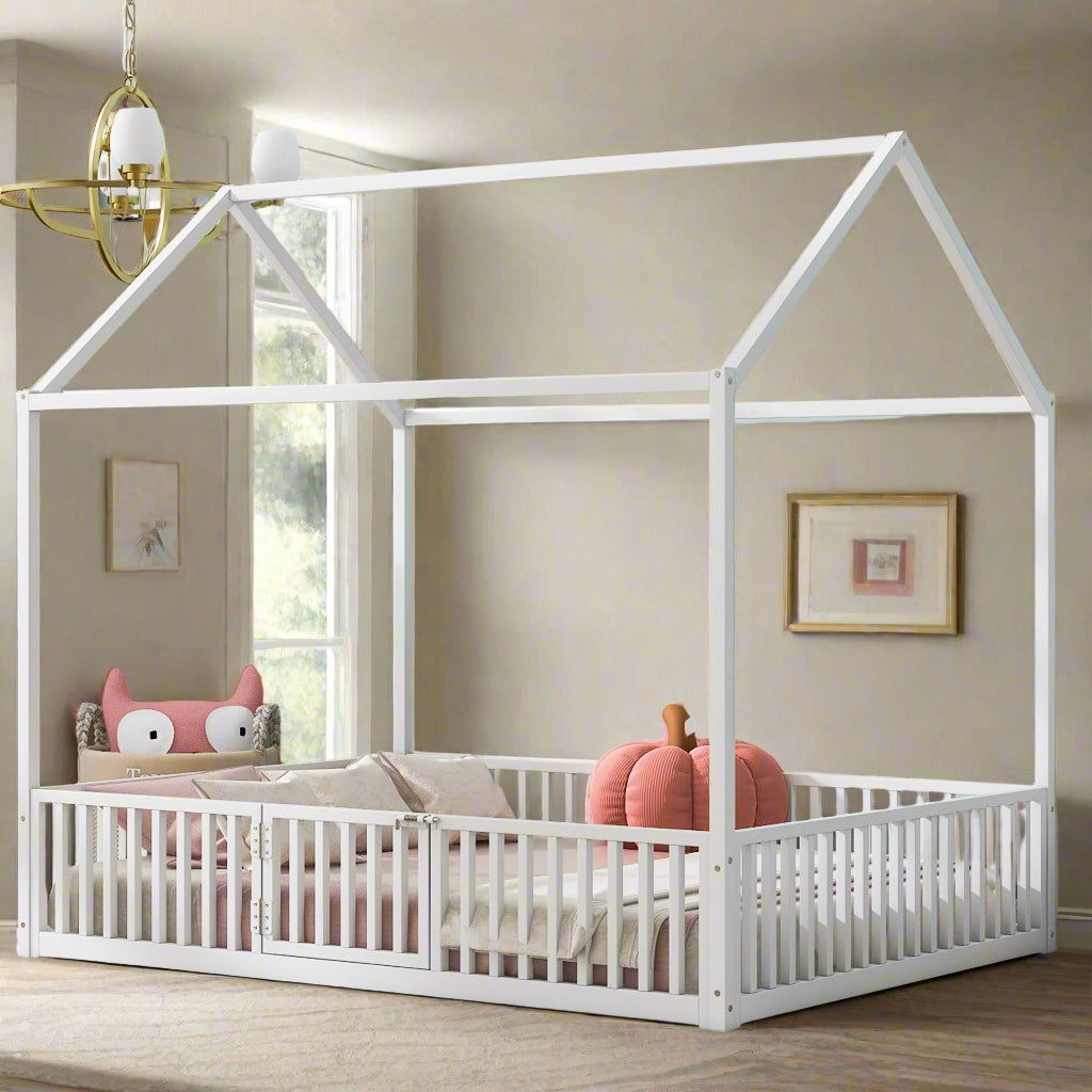 White children's house-shaped bed with pink bedding and pillows in a room with light blue walls and decorative art.