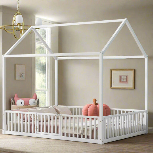 White children's house-shaped bed with pink bedding and pillows in a room with light blue walls and decorative art.